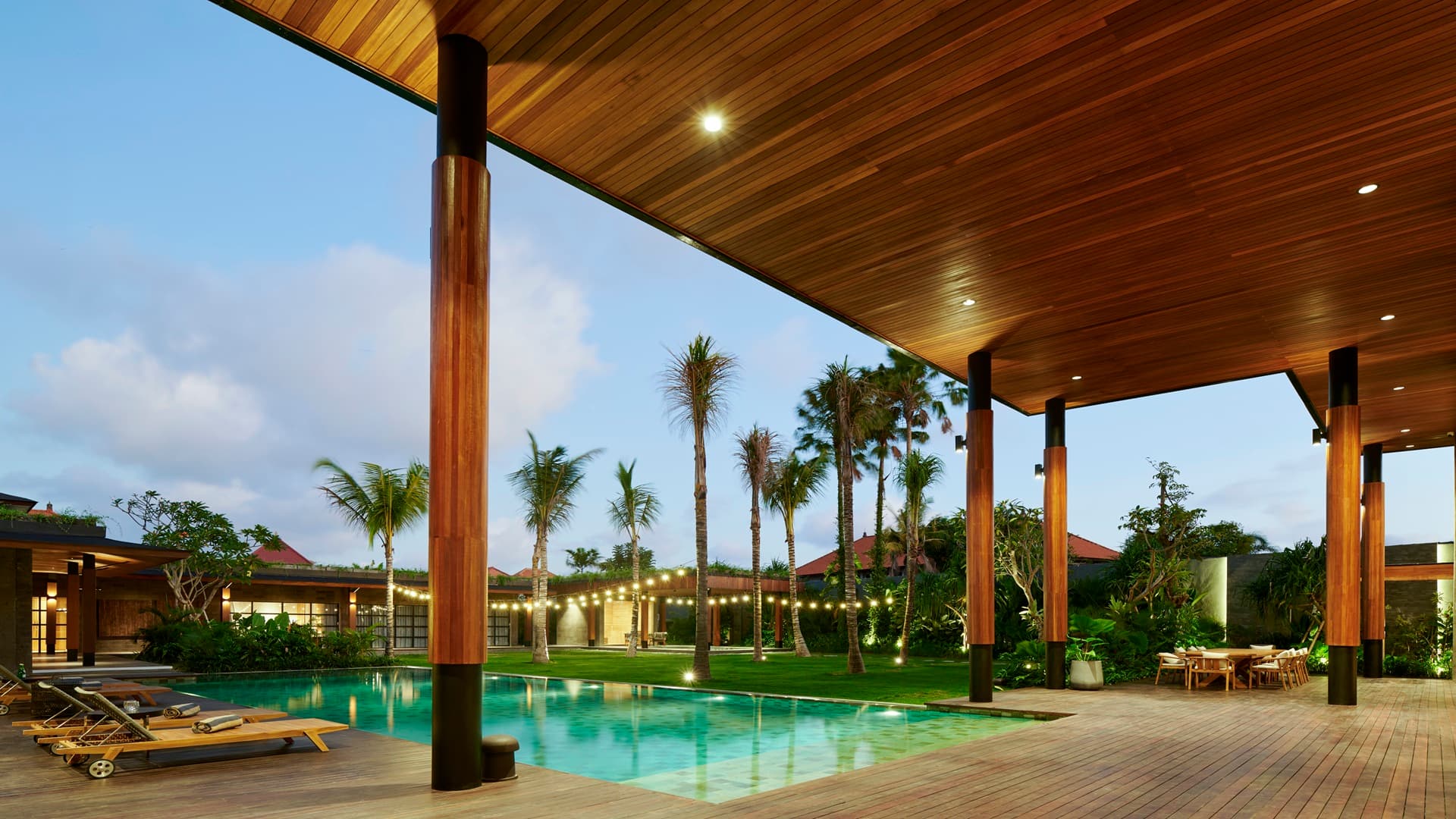 The poolside deck and dining pergola glowing at dusk